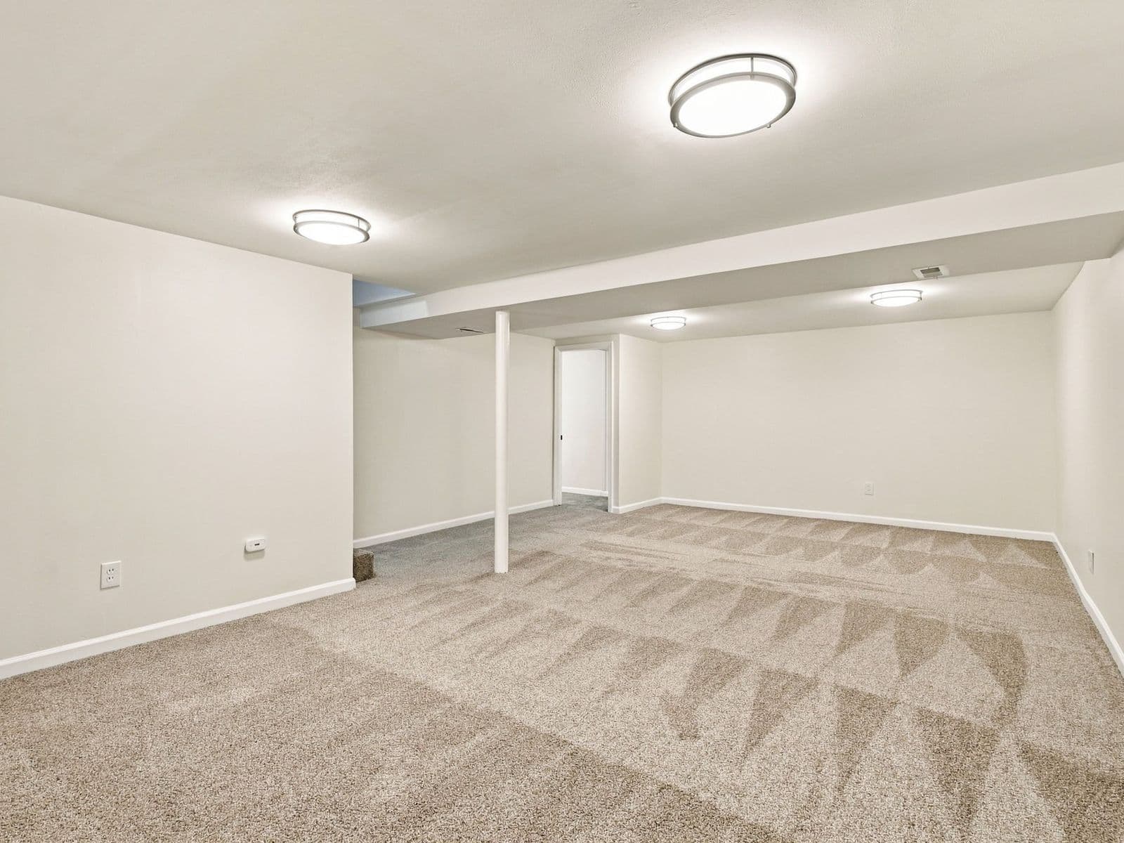 The same basement after — finished walls, new carpet, recessed and ceiling lights