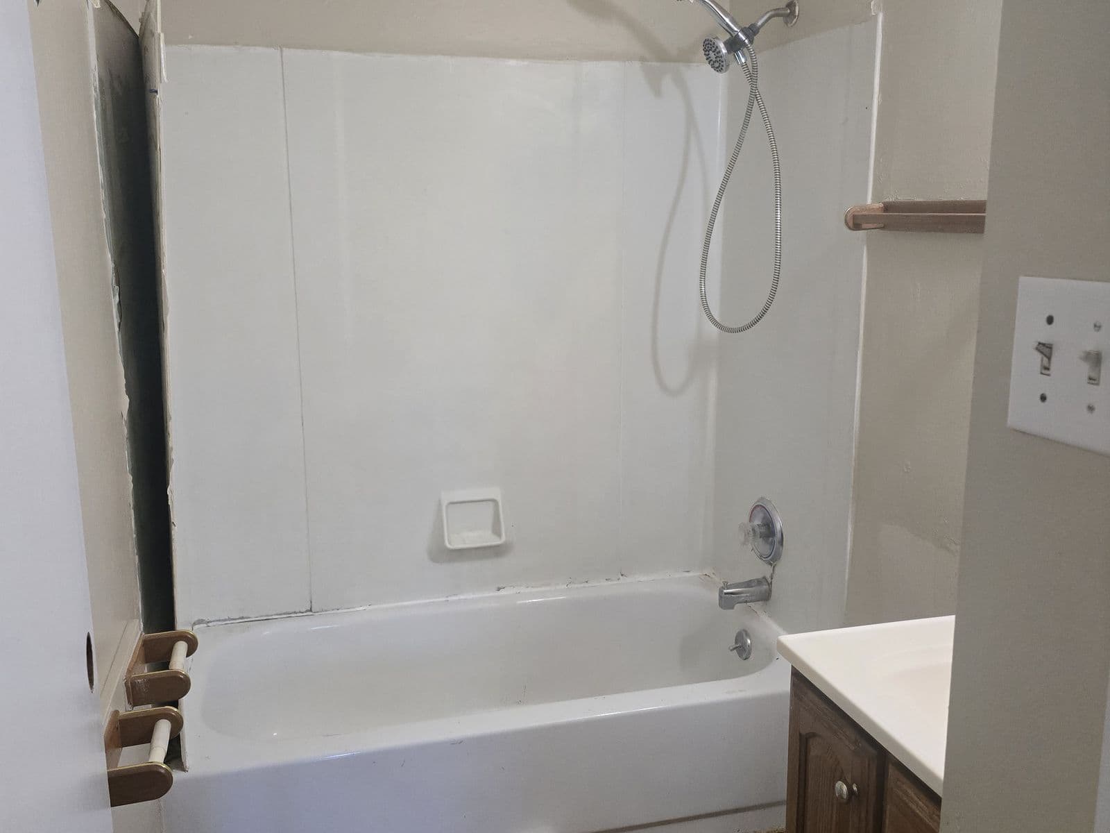 Bathroom before renovation — plastic tub surround, parquet floor, dated vanity