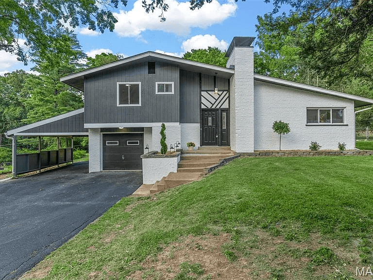 A thoughtfully updated split-level family home with gray board-and-batten siding, white painted brick, a freshly landscaped yard, and a welcoming front entry